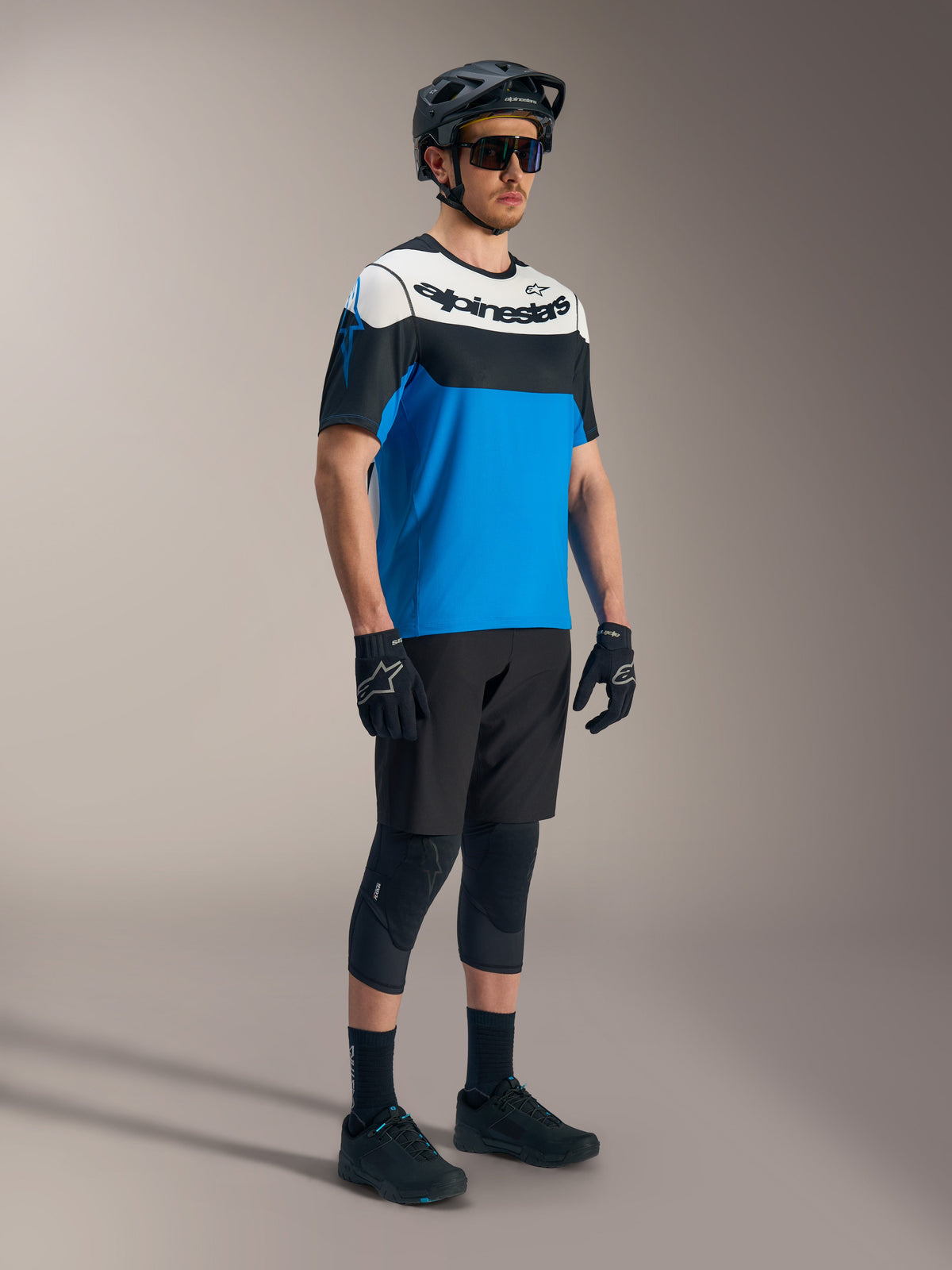 Jersey Alpinestars A-Dura Race SS azul, negro y blanco, con shorts A-Dura Ride y equipo protector de MTB.