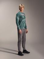 Alpinestars A-Dura Hollow Camo Long Sleeve Jersey, Silver Pine Camo, usado por un modelo con pantalones grises y zapatillas negras, con un patrón de camuflaje verde y un llamativo logotipo ASTARS blanco en el pecho, equipamiento de MTB de alto rendimiento