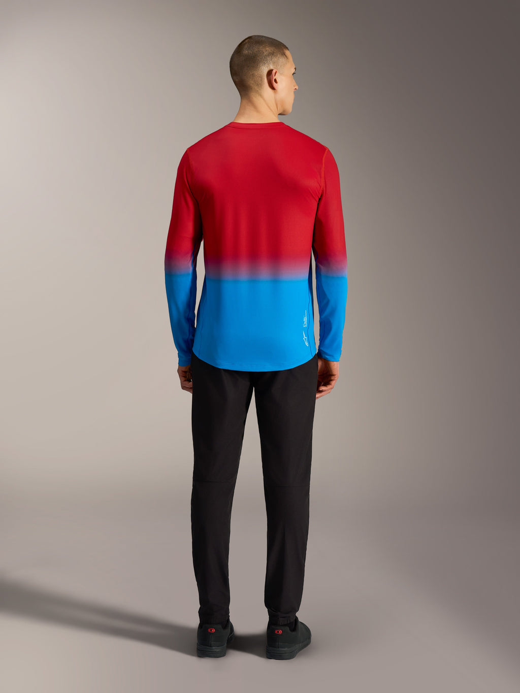 Camiseta MTB Alpinestars A-Dura ASTARS 2.0 con degradado rojo brillante y azul, vista trasera en modelo.