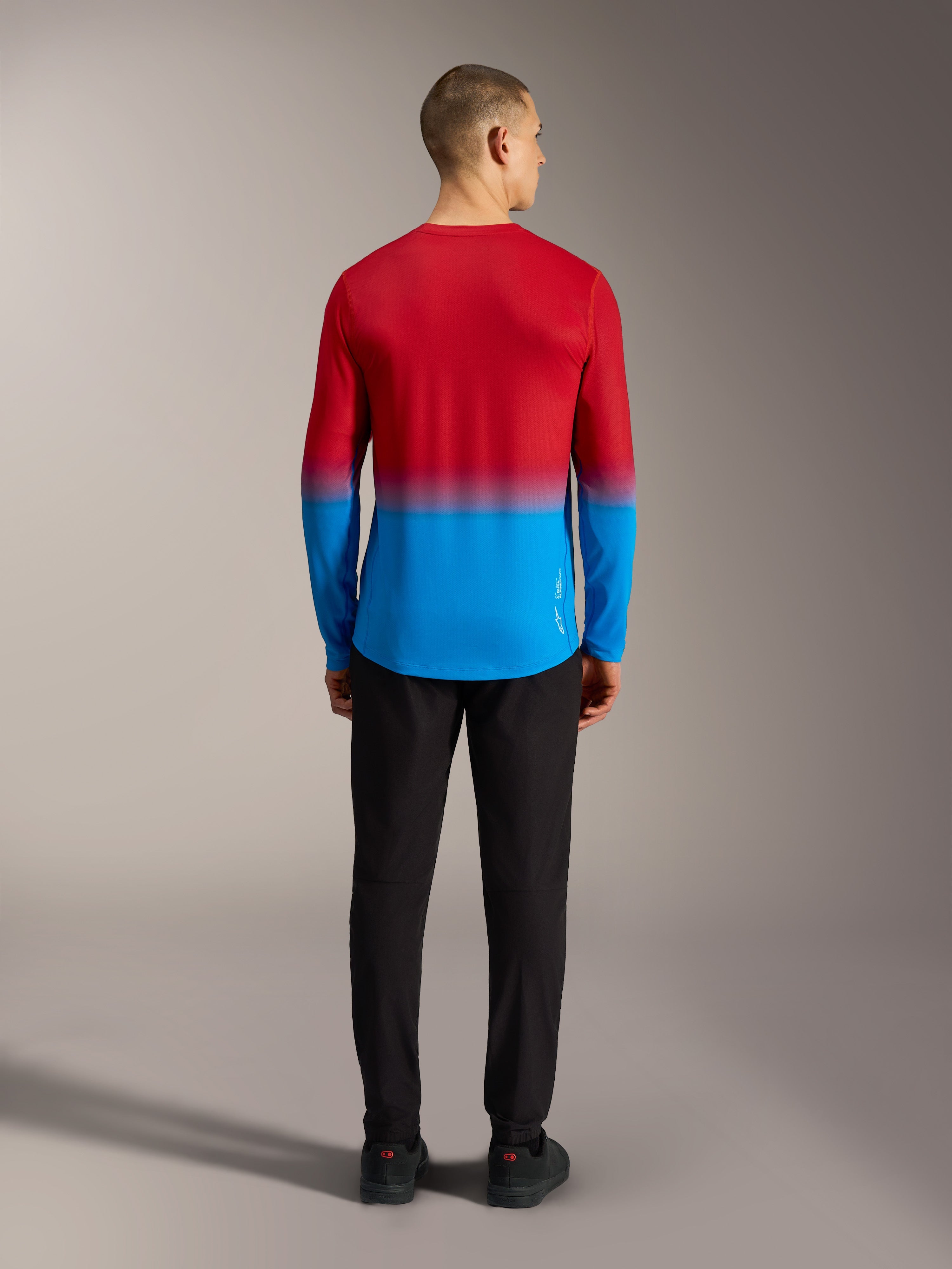 Camiseta MTB Alpinestars A-Dura ASTARS 2.0 con degradado rojo brillante y azul, vista trasera en modelo.