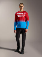 Camiseta MTB A-Dura ASTARS 2.0 de manga larga, degradado rojo y azul con logos blancos, combinada con pantalones negros.