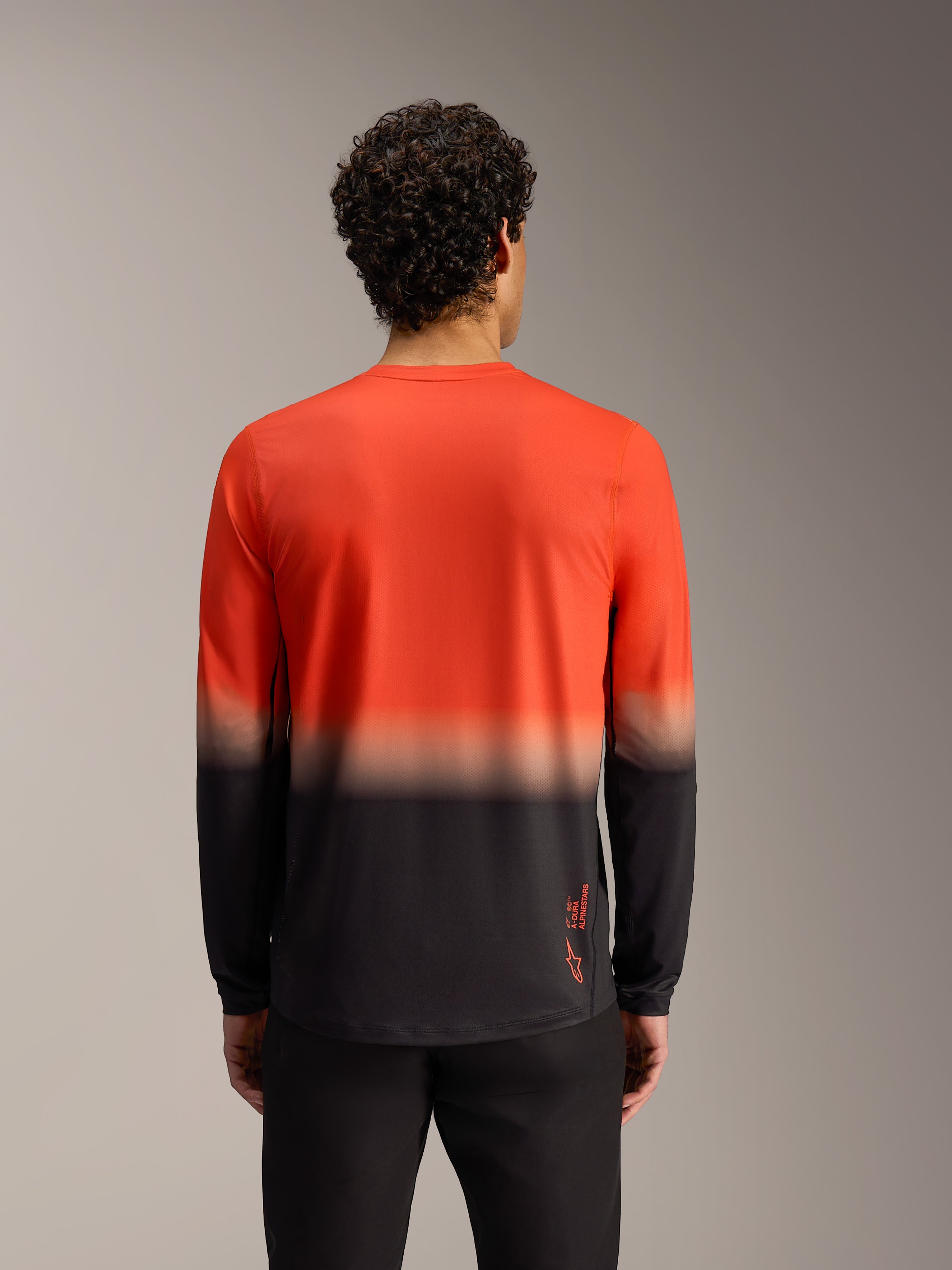 Camiseta Alpinestars A-Dura ASTARS 2.0 de manga larga, degradado naranja y negro, vista posterior técnica para trail MTB.