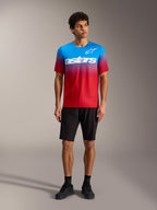 Maillot A-Dura ASTARS 2.0 en degradado rojo y azul con logo blanco, junto a shorts de MTB y calzado negros.