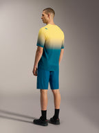 Maillot A-Dura ASTARS 2.0 de manga corta en degradado amarillo y verde azulado con shorts azules de alto rendimiento.
