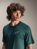 Alpinestars A-Dura Rise Jersey de manga corta, verde Silver Pine, usado por un modelo, con un pequeño logotipo blanco de Astars en el pecho, tejido jacquard de alto rendimiento, ropa casual para ciclismo de montaña