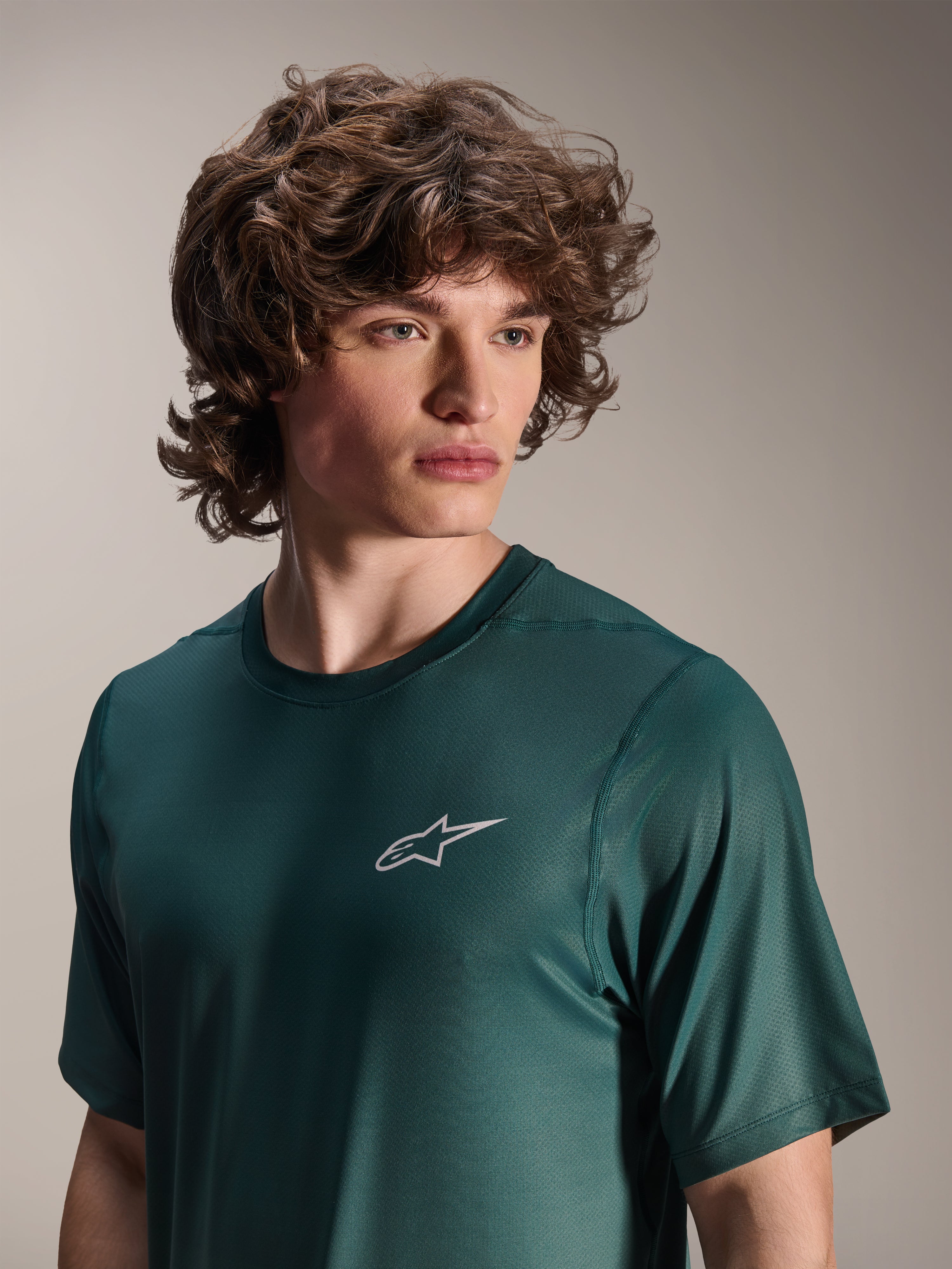 Alpinestars A-Dura Rise Jersey de manga corta, verde Silver Pine, usado por un modelo, con un pequeño logotipo blanco de Astars en el pecho, tejido jacquard de alto rendimiento, ropa casual para ciclismo de montaña