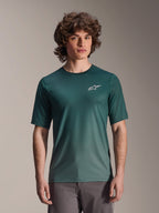 Alpinestars A-Dura Rise Jersey de manga corta, verde oscuro Silver Pine, usado por un modelo, con logotipo blanco de Astars en el pecho, tejido jacquard ligero que absorbe la humedad, camiseta técnica para ciclismo de montaña de estilo casual