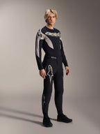 Modelo masculino vistiendo pantalones Alpinestars A-Supra Melt y jersey de manga larga a juego, negro con patrones curvos en gris claro, con destacados logotipos Astars blancos en las piernas y marca en el pecho, equipamiento profesional para ciclismo de montaña.