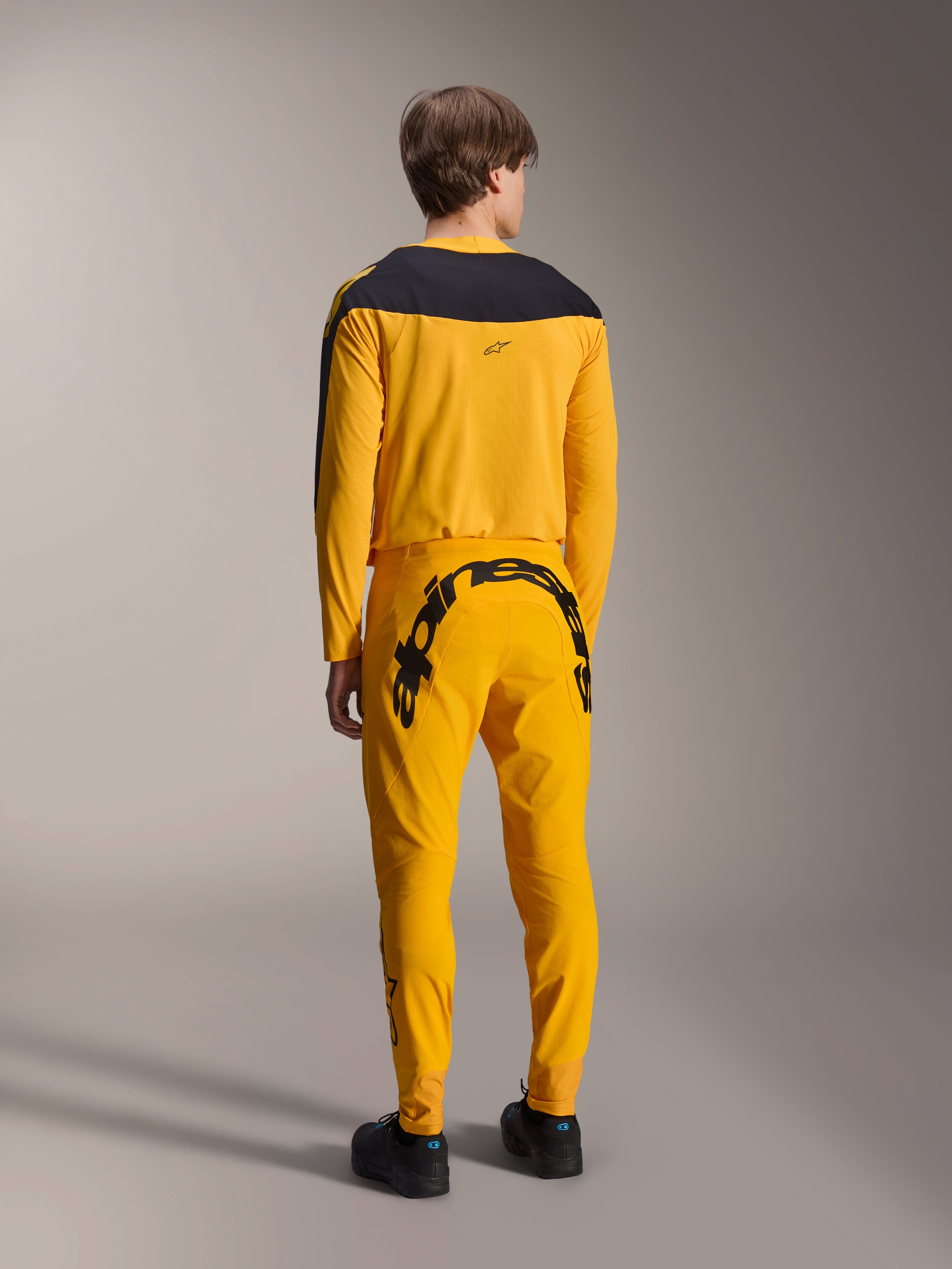 Alpinestars Limited Edition A-Supra Melt Gold Gear-Set, MTB Jersey and Pants, Dark Yellow and Black, rear view featuring large Alpinestars wordmark on the seat and black yoke on the jersey, performance mountain bike apparel