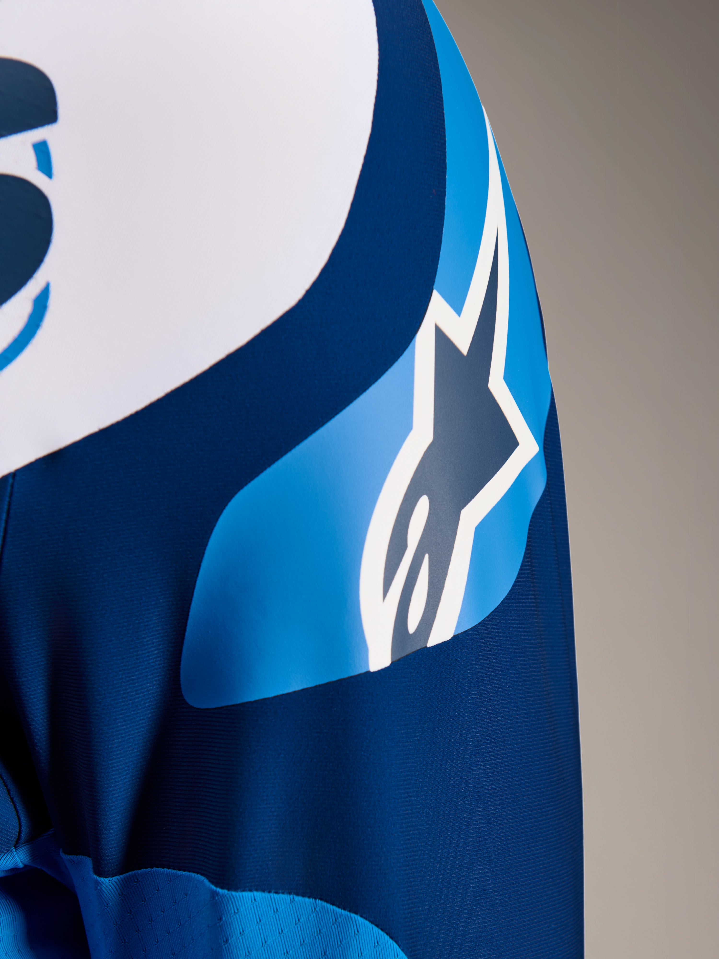 Alpinestars A-Supra Melt Jersey, jersey de MTB de manga larga en azul, primer plano de la manga que muestra el gráfico del logotipo ASTARS y el tejido microperforado para ventilación