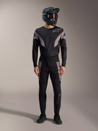 Equipación MTB A-Supra Elite negra con jersey de manga larga, pantalones con logos grises y casco integral.