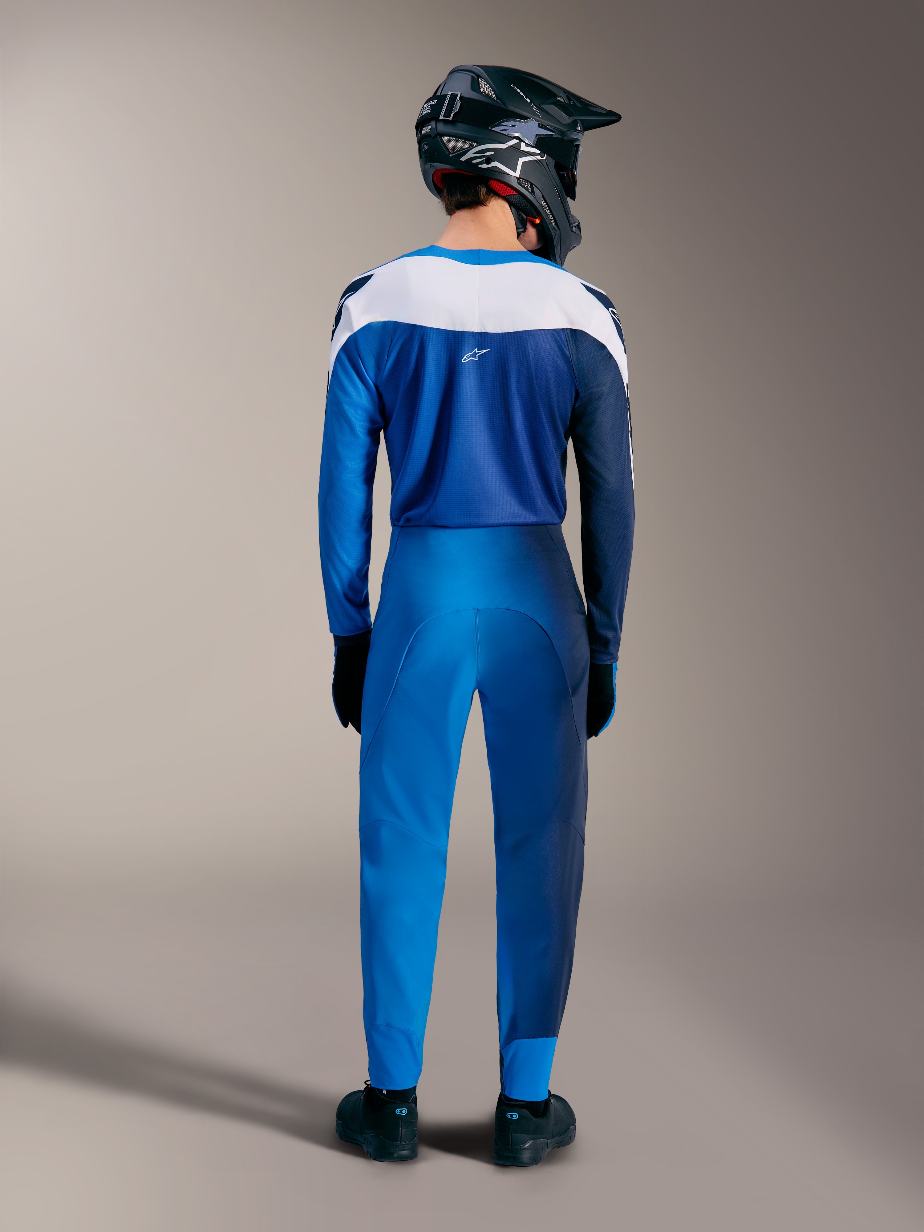 Kit MTB Alpinestars A-Supra Elite azul brillante, vista trasera de jersey degradado y pantalones técnicos con paneles blancos.