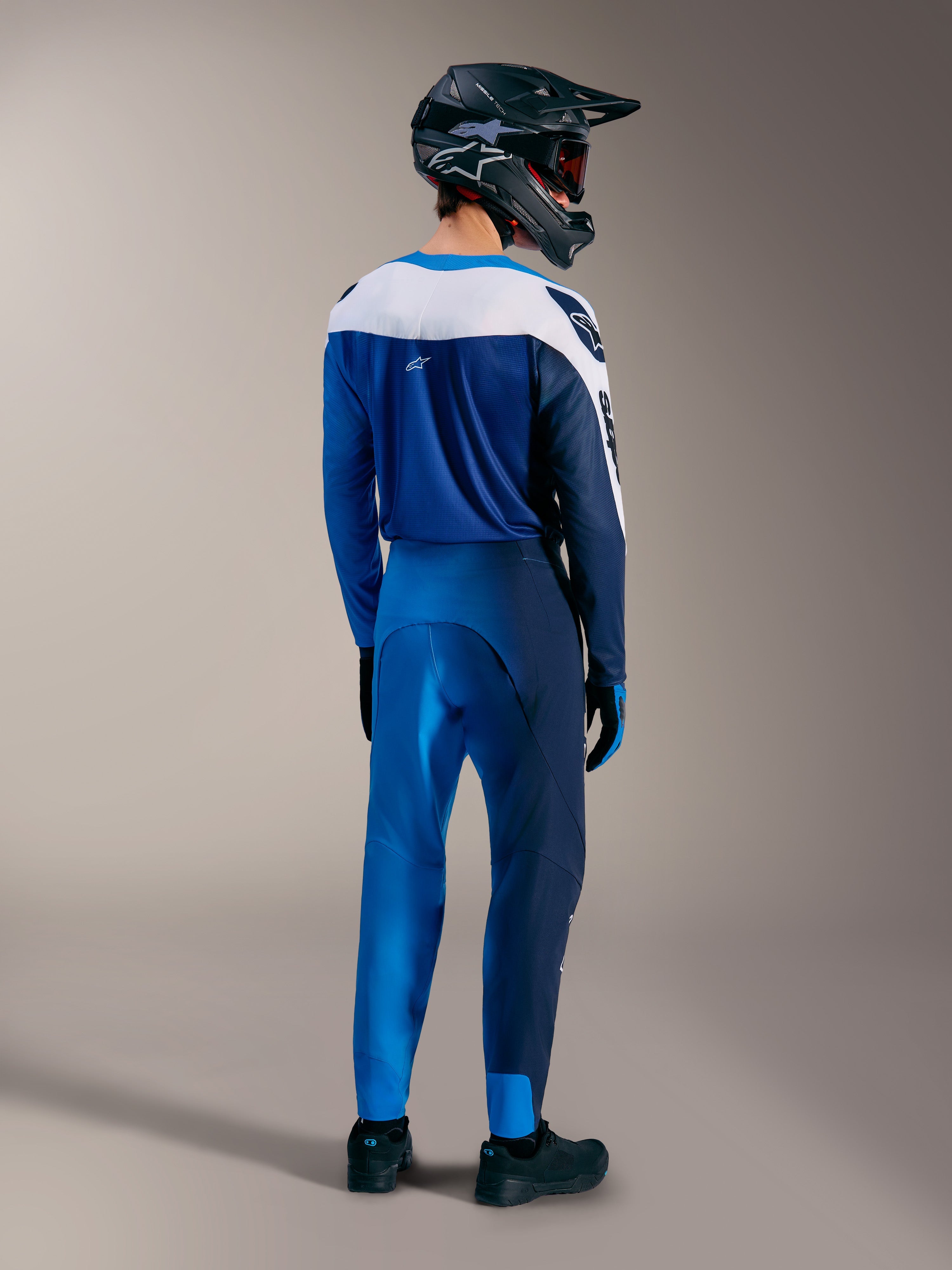 Equipo MTB A-Supra Elite en azul brillante degradado, con jersey y pantalones a juego por detrás y casco integral.