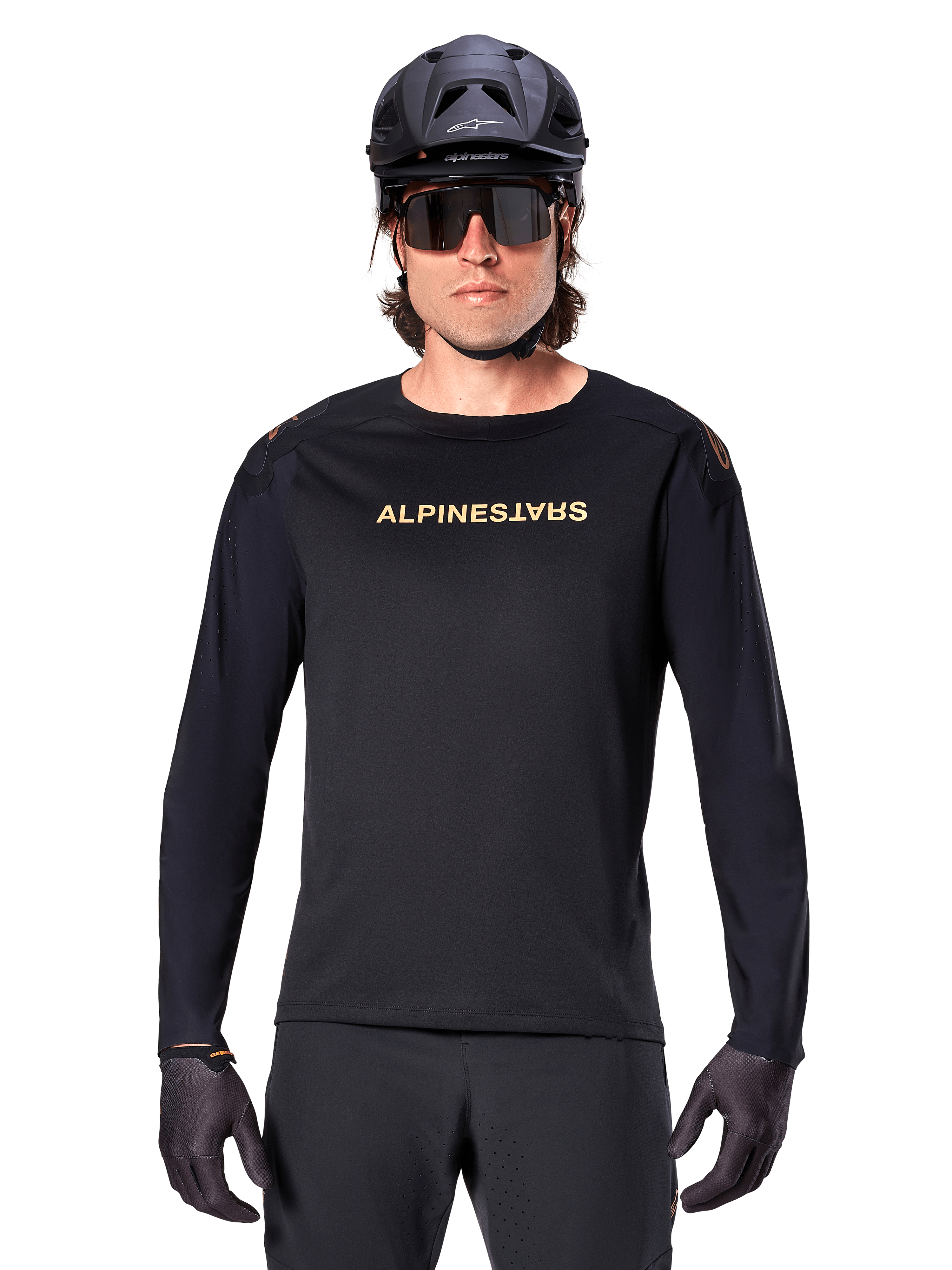 Jersey de manga larga Alpinestars A-Aria Polartec Switch, negro, logotipo de Alpinestars en dorado en el pecho, usado con un casco de MTB negro, gafas de sol oscuras y guantes negros, equipamiento profesional para trail en bicicleta de montaña