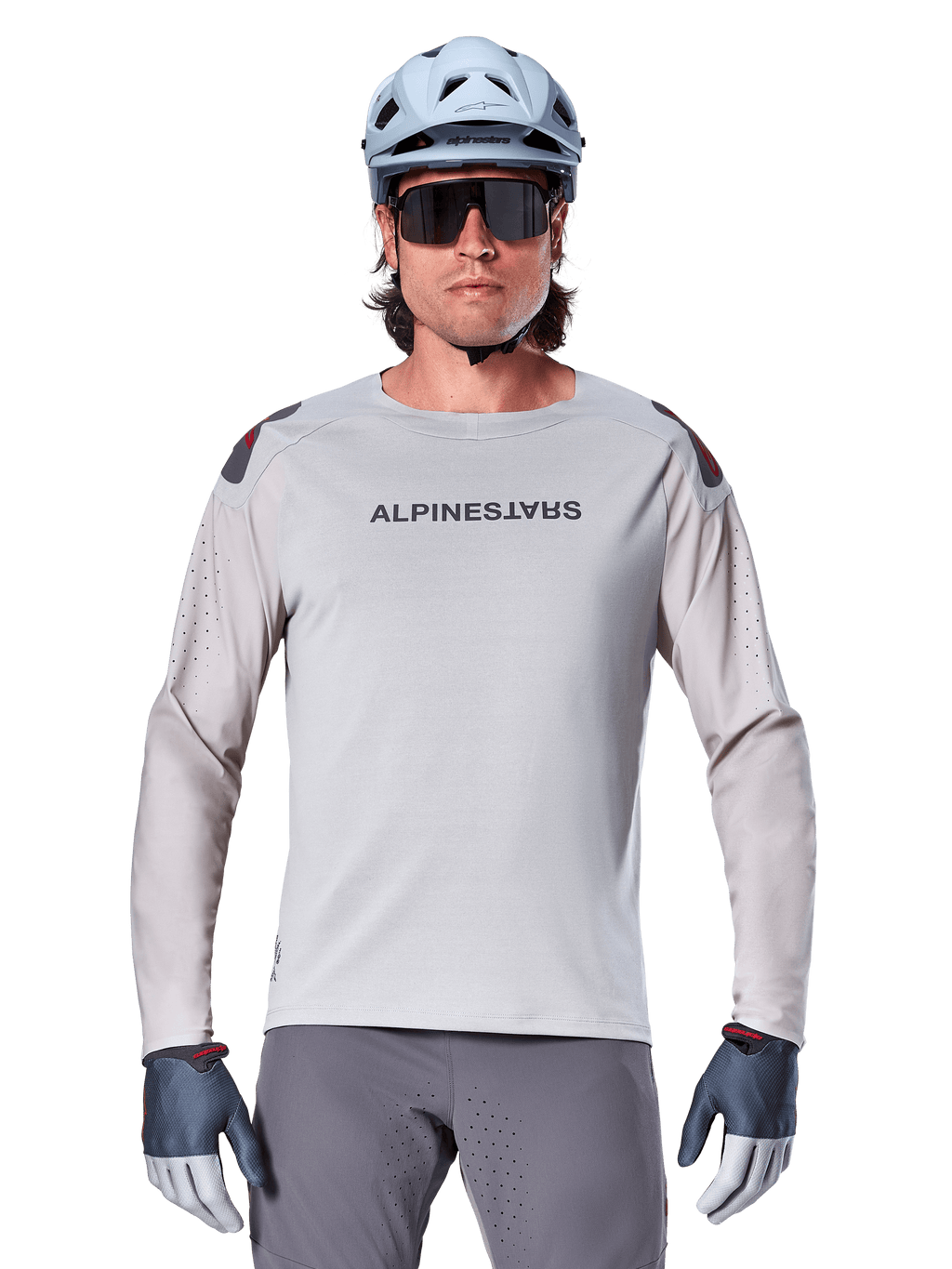 Alpinestars A-Aria Polartec Switch Jersey de manga larga, jersey de ciclismo de montaña en color gris claro con perforaciones láser en las mangas y logotipo en el pecho, usado con casco azul claro, gafas de sol y guantes grises