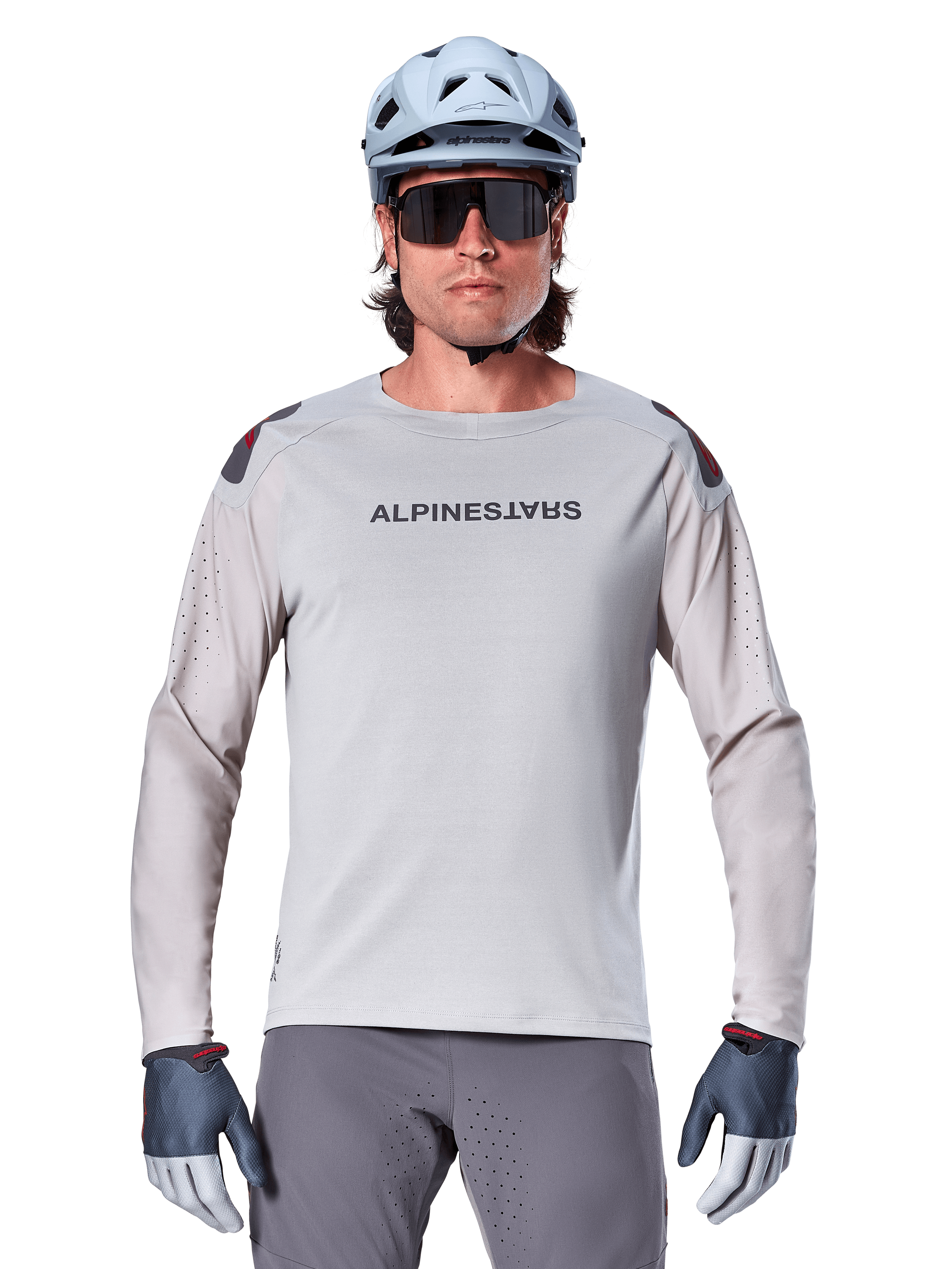 Alpinestars A-Aria Polartec Switch Jersey de manga larga, jersey de ciclismo de montaña en color gris claro con perforaciones láser en las mangas y logotipo en el pecho, usado con casco azul claro, gafas de sol y guantes grises