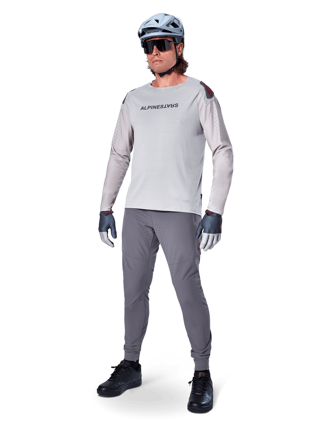 Alpinestars A-Aria Polartec Switch Jersey, jersey de MTB de manga larga, gris claro, usado con pantalones de MTB gris oscuro, casco y guantes, con mangas perforadas con láser y logotipo de Alpinestars en el pecho.