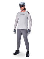 Alpinestars A-Aria Polartec Switch Jersey, jersey de MTB de manga larga, gris claro, usado con pantalones de MTB gris oscuro, casco y guantes, con mangas perforadas con láser y logotipo de Alpinestars en el pecho.