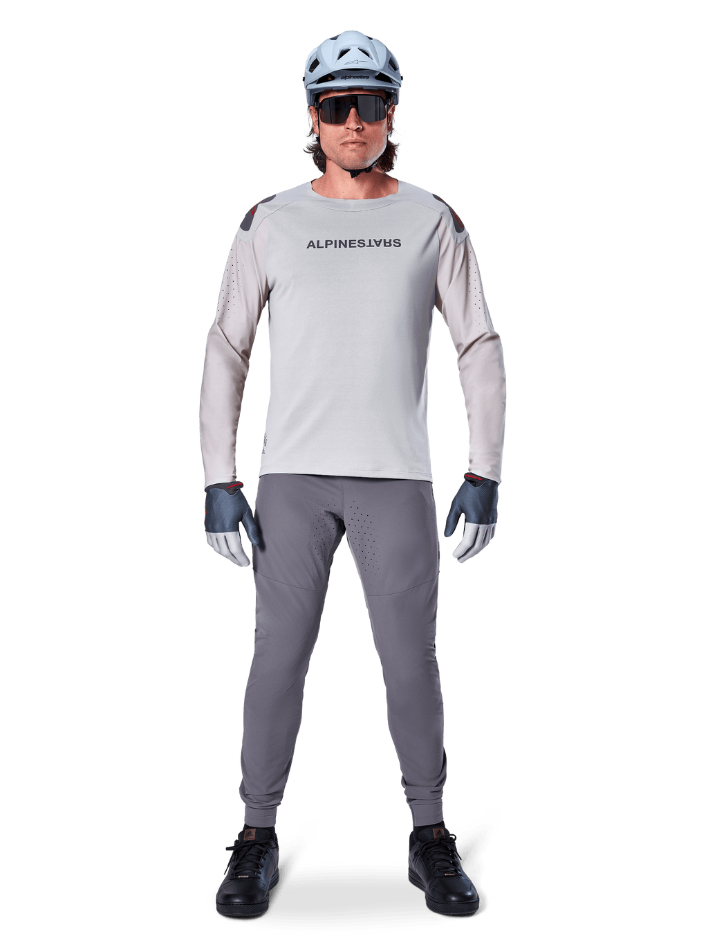 Jersey Alpinestars A-Aria Polartec Switch de manga larga, gris claro, usado por un ciclista de montaña con pantalones de MTB gris oscuro, casco azul claro y gafas de sol, con logotipo en el pecho y ventilación perforada por láser en las mangas, equipamiento completo para ciclismo todoterreno