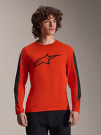 Alpinestars Jersey A-Dura Insert Astar - Manga Larga, naranja Spicy con logo Astar negro, con inserciones duraderas gris oscuro en las mangas, usado por un modelo masculino, ropa de ciclismo MTB de alto rendimiento
