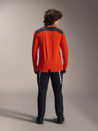 Jersey Alpinestars A-Dura Insert Astar de manga larga en Spicy Orange, vista trasera que muestra el panel de los hombros en gris carbón, usado con pantalones Alpinestars negros y calzado negro, fotografía de estudio profesional de equipamiento de alto rendimiento para MTB