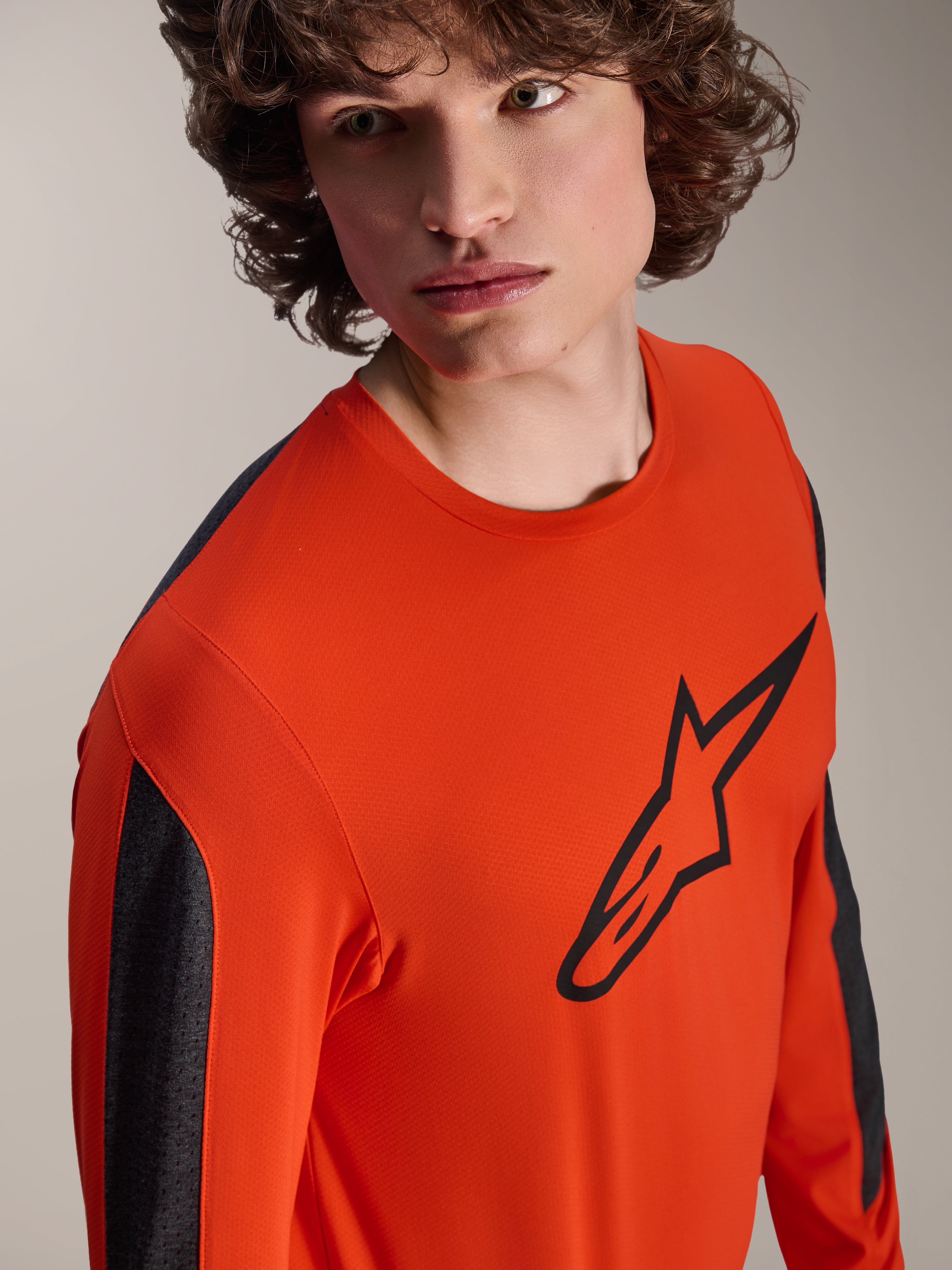 Alpinestars Jersey de manga larga A-Dura Insert Astar, jersey de MTB color Spicy Orange con gran logo Astar negro en el pecho, paneles de las mangas en gris oscuro, primer plano de estudio de un modelo, tejido técnico texturizado.