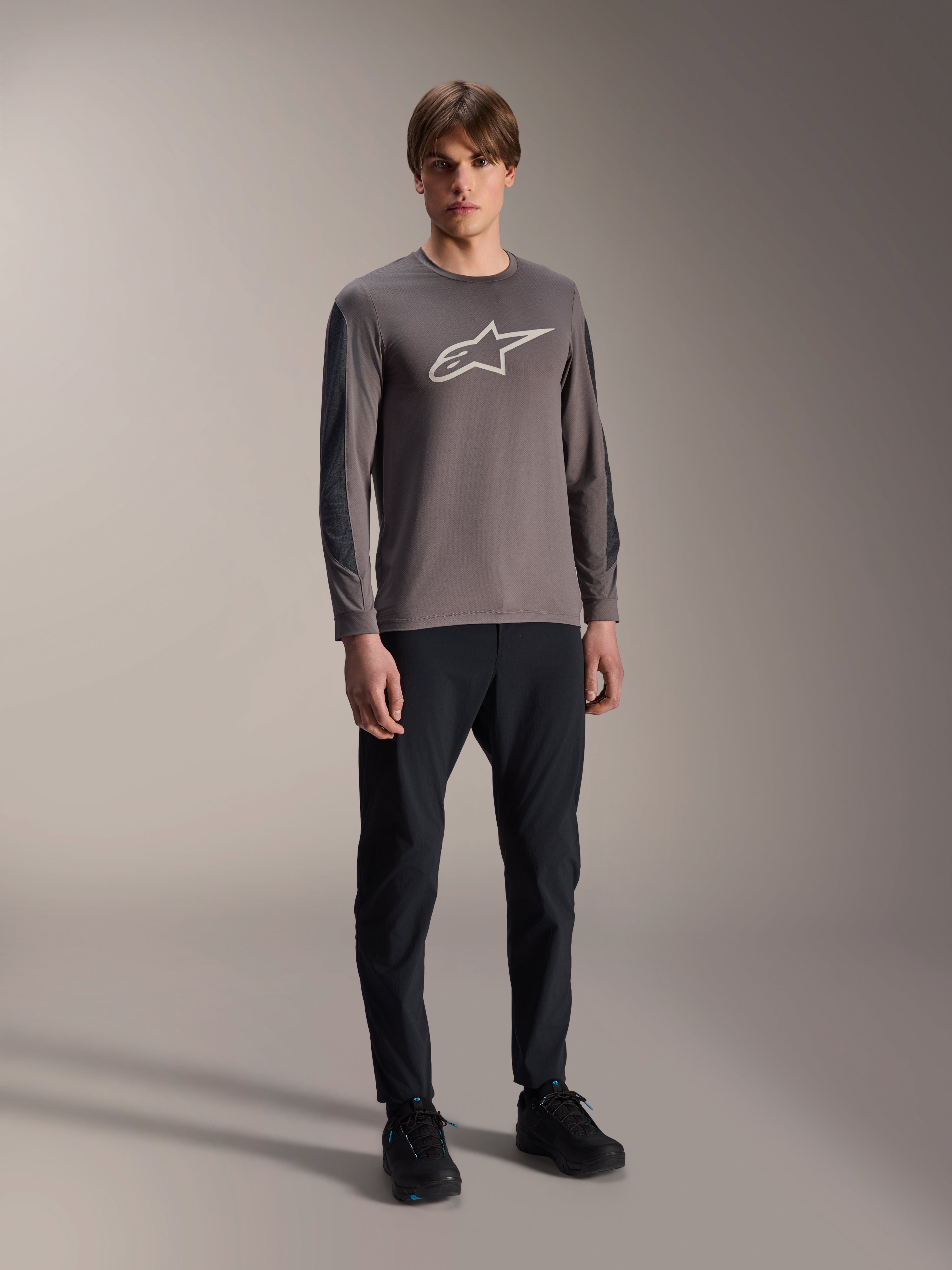 Jersey Alpinestars A-Dura Insert Astar, jersey de MTB de manga larga, gris oscuro, con un gran logotipo blanco en el pecho, usado con pantalones técnicos negros y calzado negro, ropa de ciclismo todoterreno