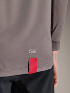 Alpinestars A-Dura Insert Astar Jersey, jersey de MTB de manga larga, gris oscuro, detalle en primer plano del dobladillo inferior trasero con la marca A-DURA en blanco y una etiqueta de tela roja distintiva de ASTARS, tejido técnico con textura