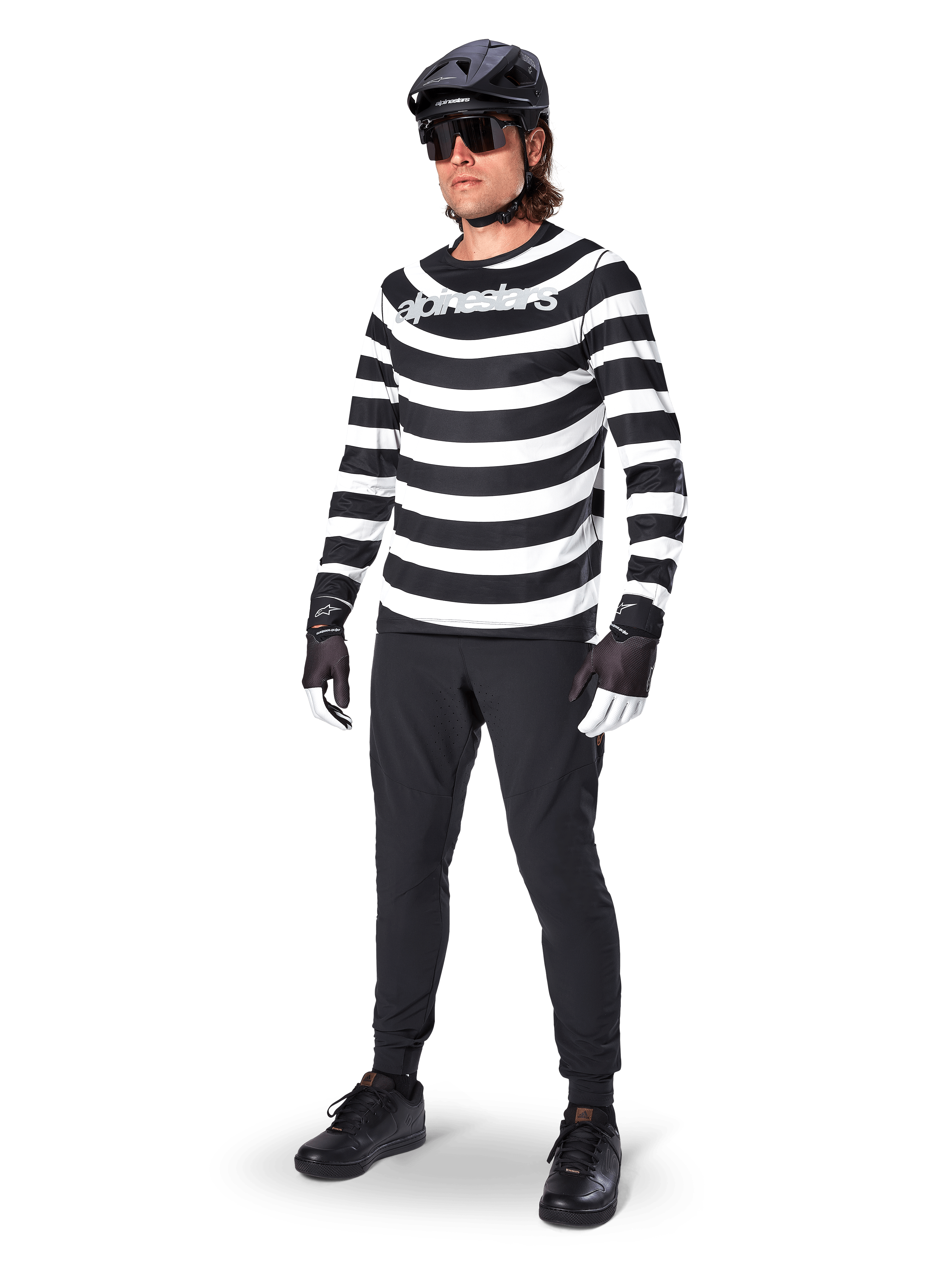 Jersey de manga larga Alpinestars A-Aria Oscar, negro y blanco con llamativas franjas horizontales en espiral, logotipo curvo de Alpinestars en blanco, equipamiento de MTB de alto rendimiento usado con pantalones de ciclismo negros y casco
