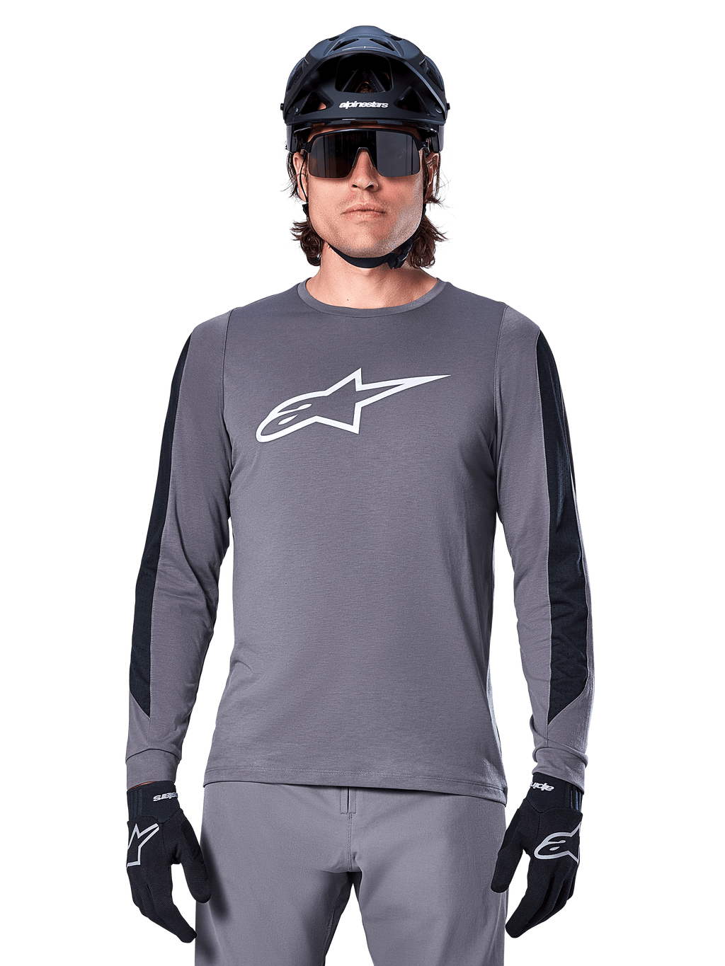 Jersey de manga larga Alpinestars A-Dura Dri Astar, gris oscuro, con un gran logotipo Astar blanco en el pecho y paneles de malla negros en los brazos, usado por un ciclista con casco negro de bicicleta de montaña y gafas de sol de alto rendimiento, ropa de ciclismo MTB