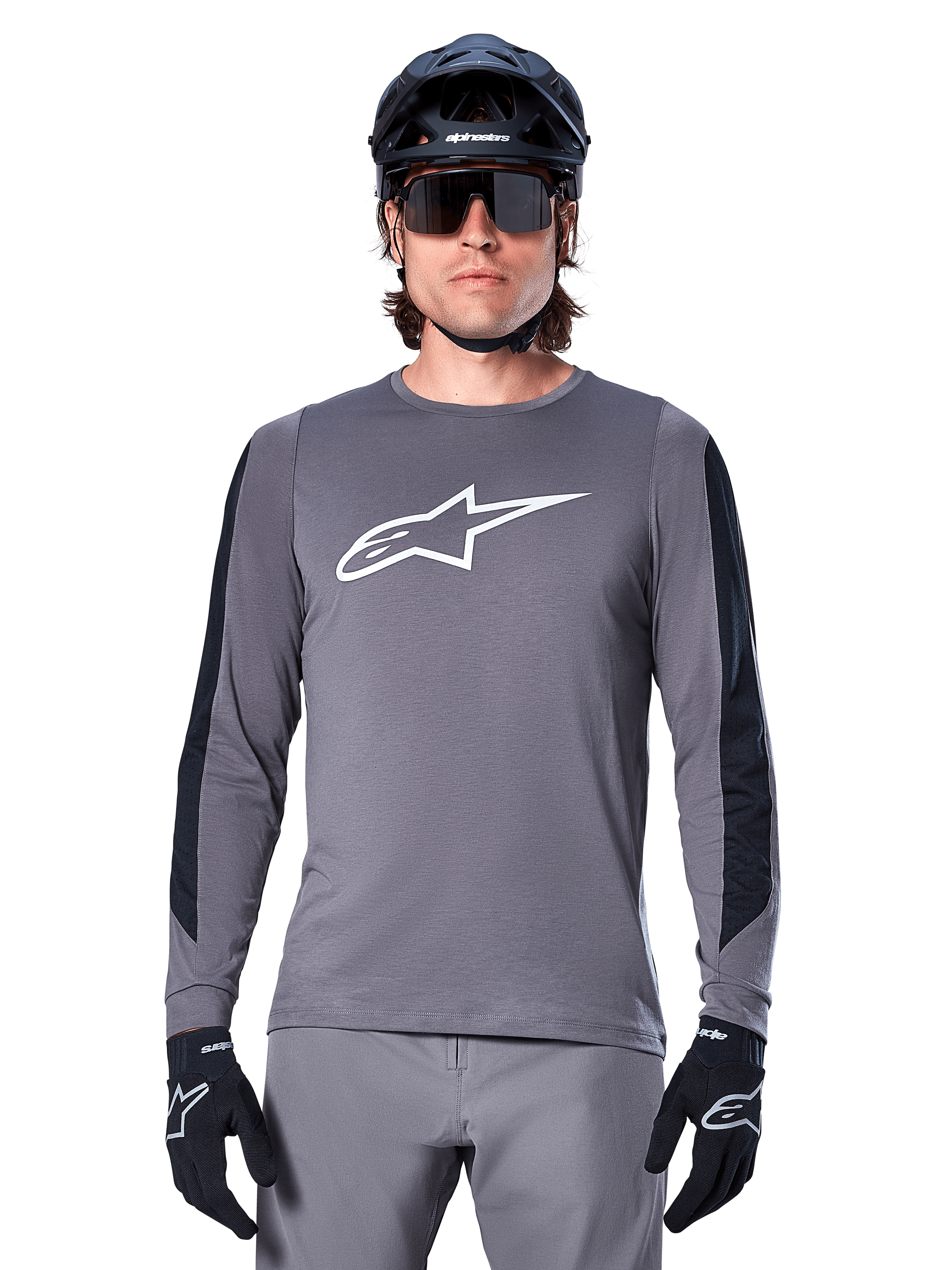 Jersey de manga larga Alpinestars A-Dura Dri Astar, gris oscuro, con un gran logotipo Astar blanco en el pecho y paneles de malla negros en los brazos, usado por un ciclista con casco negro de bicicleta de montaña y gafas de sol de alto rendimiento, ropa de ciclismo MTB