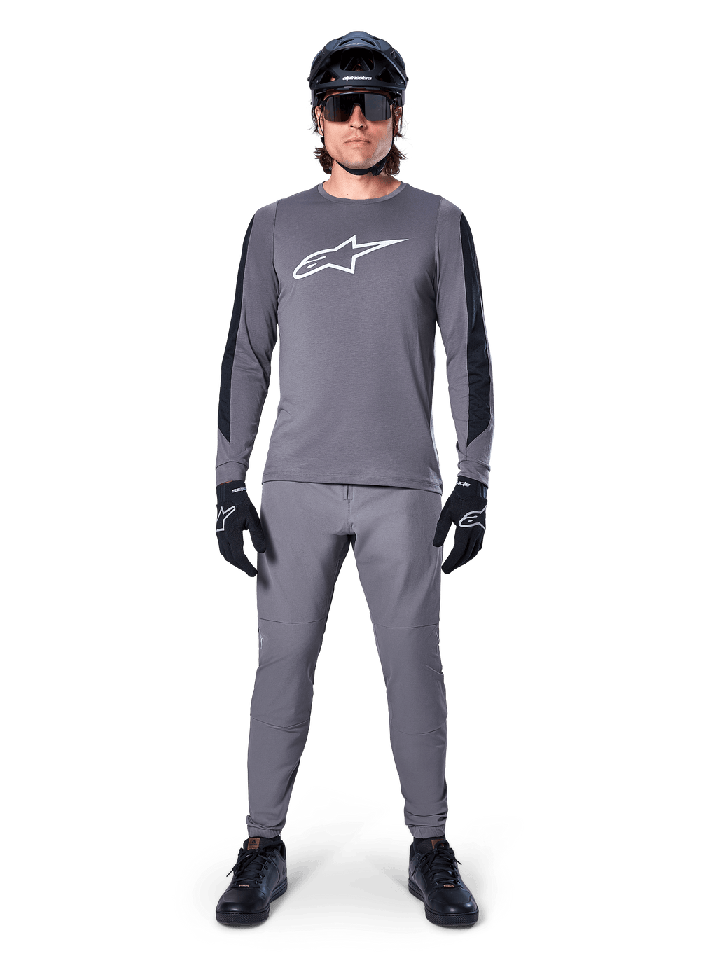 Alpinestars Jersey A-Dura Dri Astar, jersey de MTB de manga larga en gris oscuro, con el logo del pecho en blanco y paneles negros en las mangas, combinado con pantalones grises a juego, casco negro, gafas de sol y guantes para un conjunto completo de ciclismo off-road
