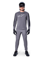 Alpinestars Jersey A-Dura Dri Astar, jersey de MTB de manga larga en gris oscuro, con el logo del pecho en blanco y paneles negros en las mangas, combinado con pantalones grises a juego, casco negro, gafas de sol y guantes para un conjunto completo de ciclismo off-road