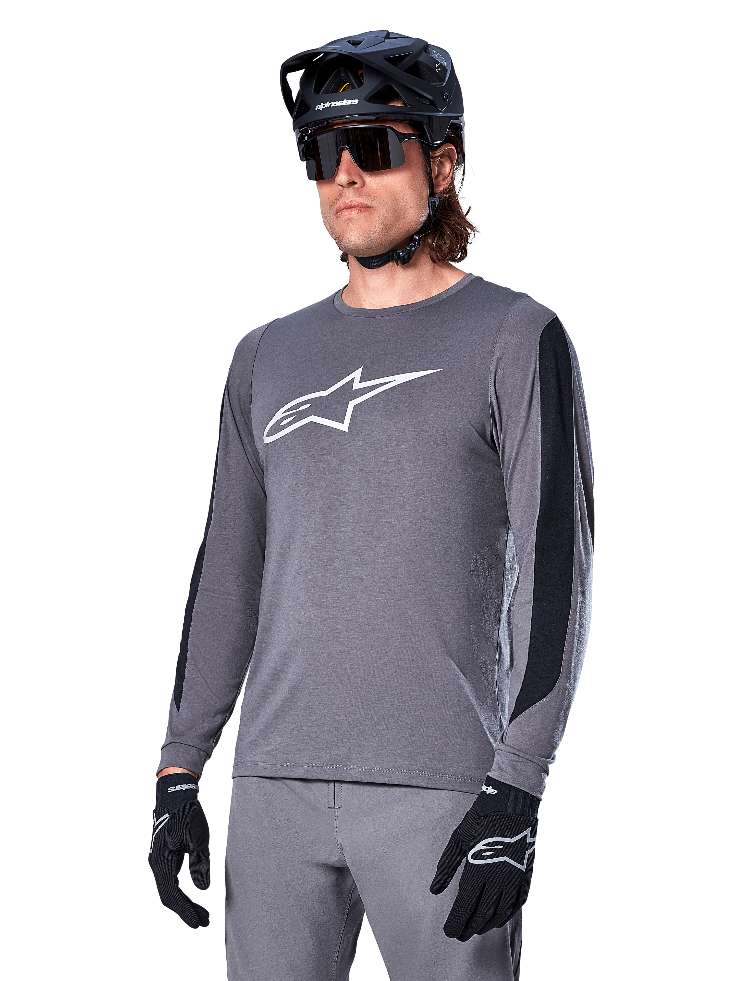 Jersey de manga larga Alpinestars A-Dura Dri Astar, gris oscuro con logotipo blanco en el pecho y paneles laterales de malla negra, jersey de ciclismo de montaña MTB, usado con casco negro, gafas de sol y pantalones grises a juego