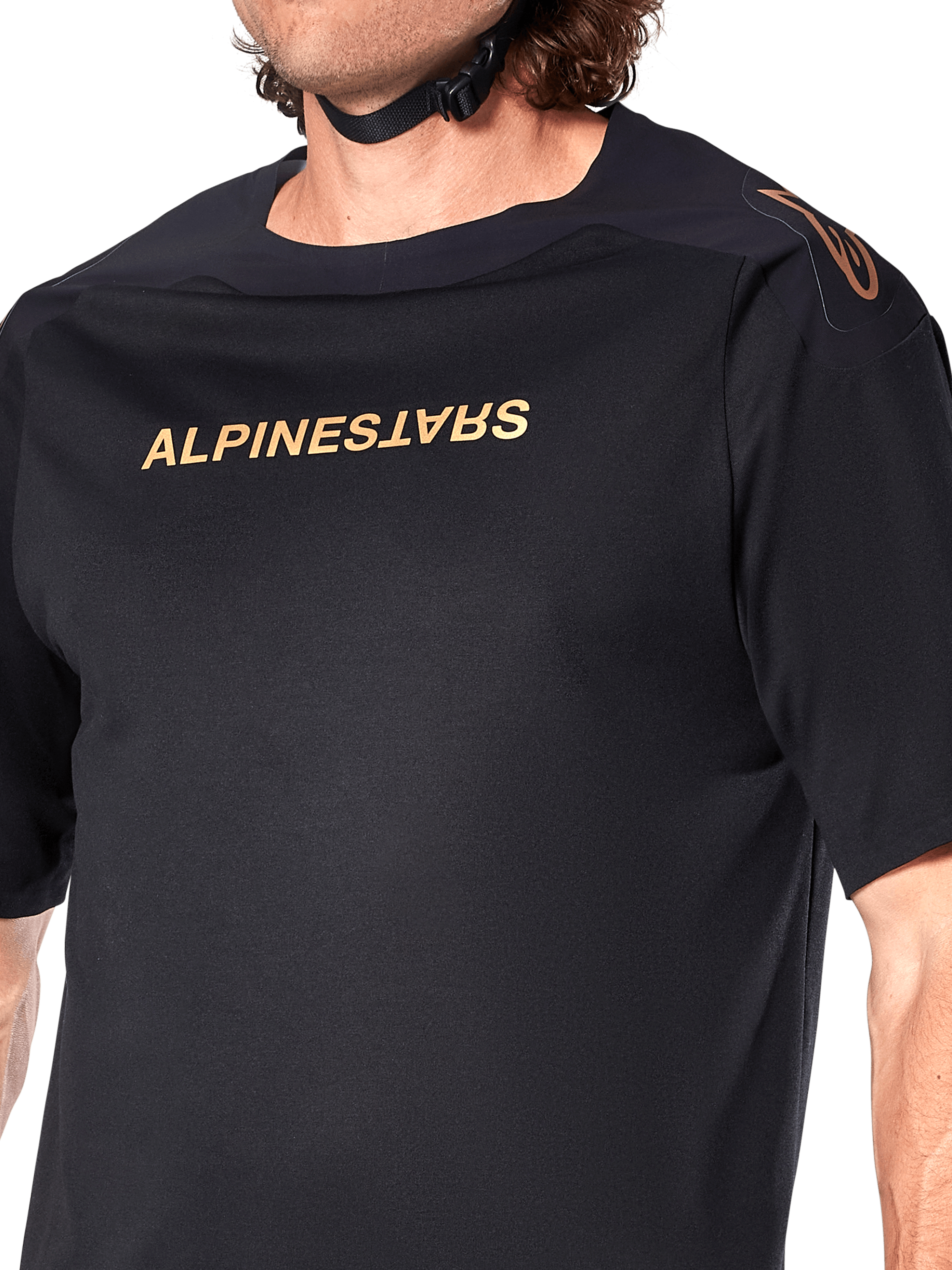 Alpinestars A-Aria Polartec Switch Jersey, camiseta de MTB de manga corta, negro, letras doradas de Alpinestars en el pecho y logotipo en el hombro, primer plano del torso superior que resalta el tejido técnico y el ajuste de alto rendimiento