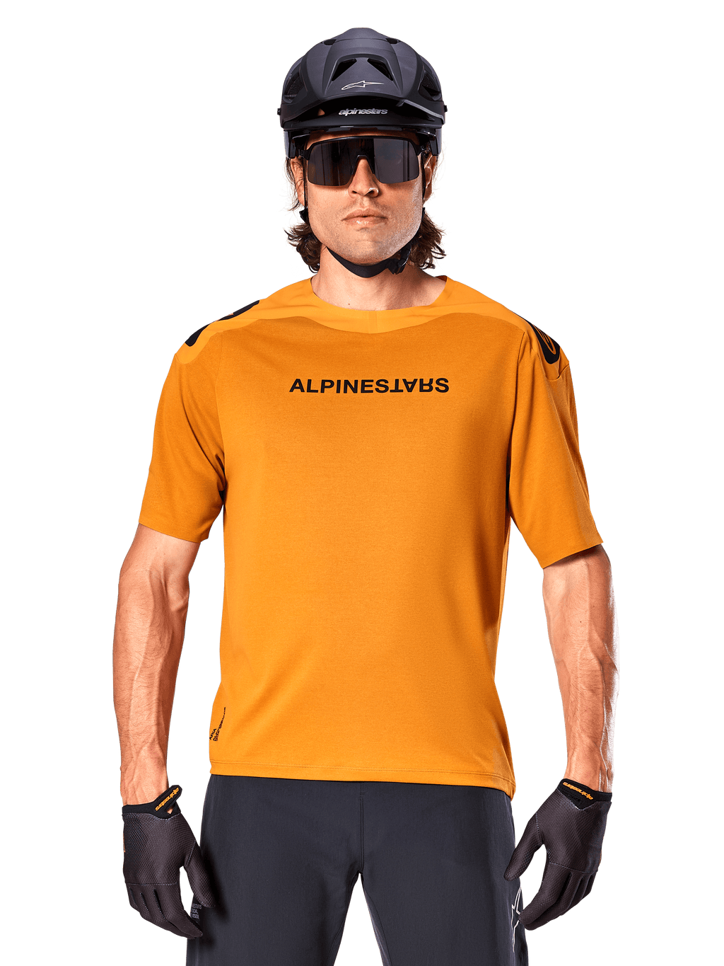 Jersey Alpinestars A-Aria Polartec Switch de manga corta, color oro oscuro, ciclista de montaña con casco negro y gafas de sol, ropa técnica de alto rendimiento para senderos de MTB