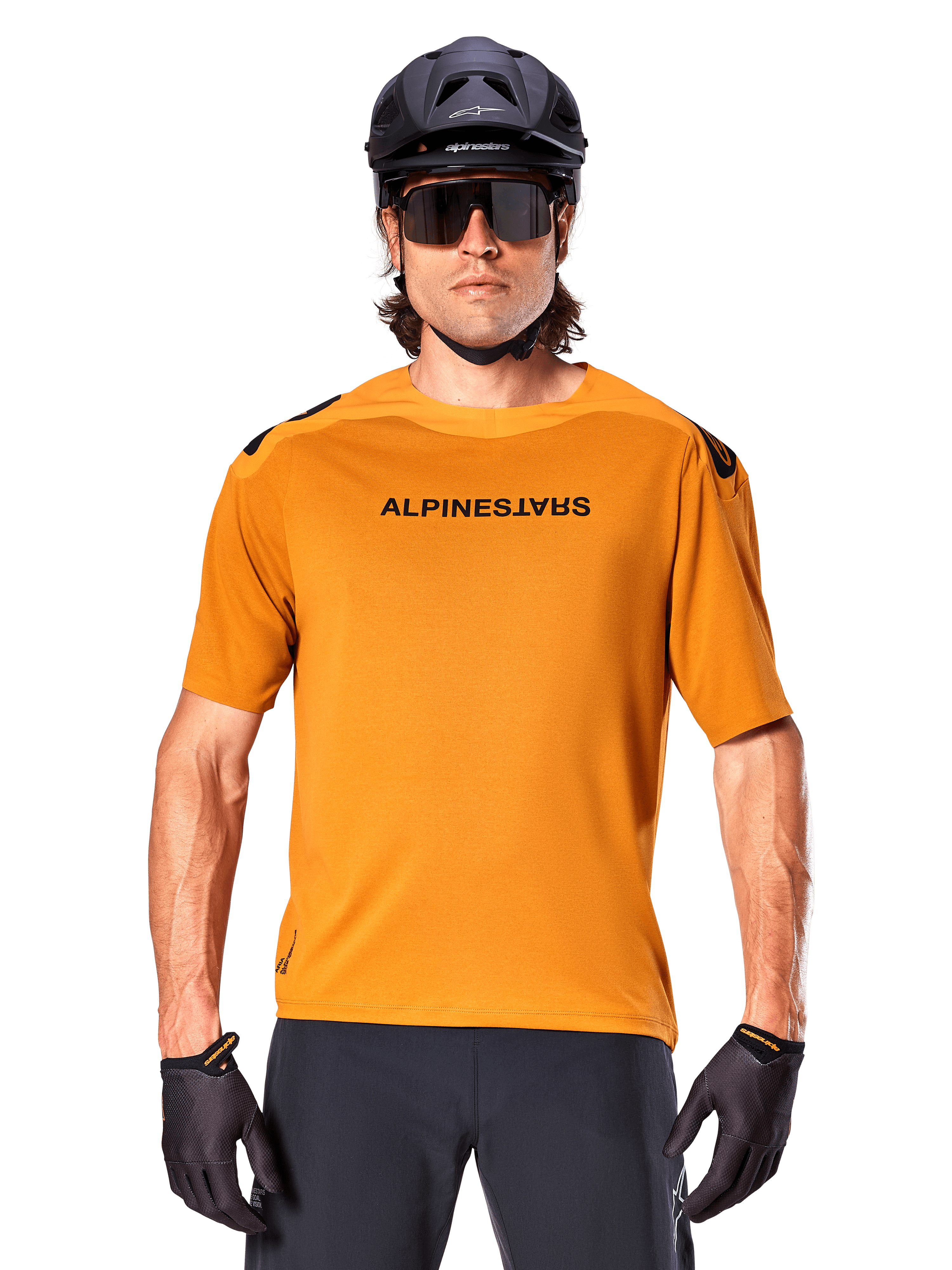 Jersey Alpinestars A-Aria Polartec Switch de manga corta, color oro oscuro, ciclista de montaña con casco negro y gafas de sol, ropa técnica de alto rendimiento para senderos de MTB