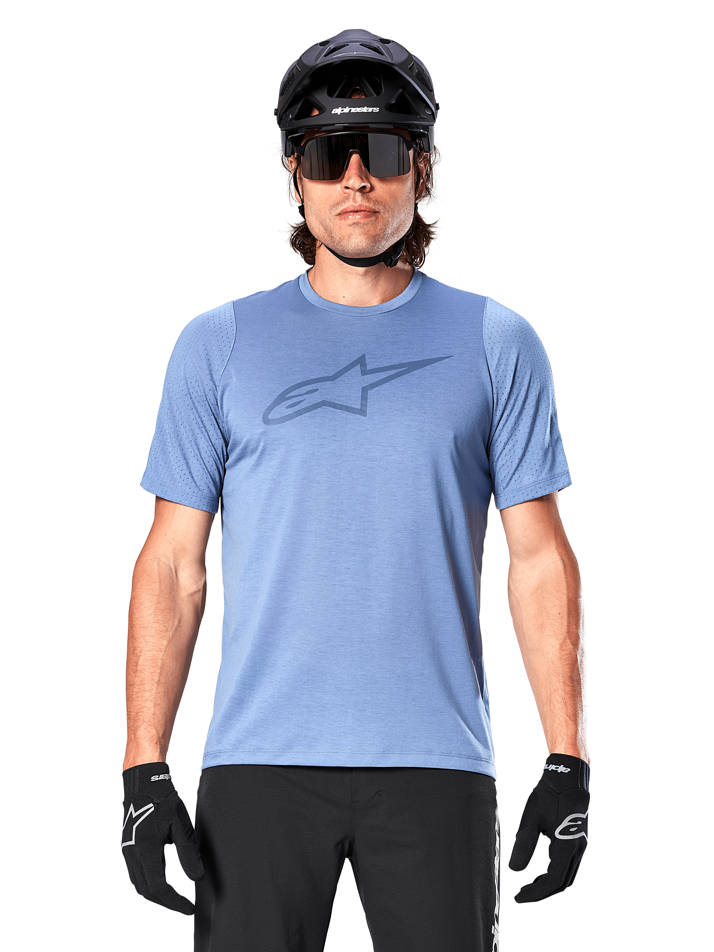 Ciclista de montaña con el jersey de manga corta Alpinestars A-Dura Dri Astar en azul Infinity, con un logotipo sutil en el pecho y paneles de malla, complementado con casco negro, gafas de sol y guantes negros para un conjunto técnico de ciclismo