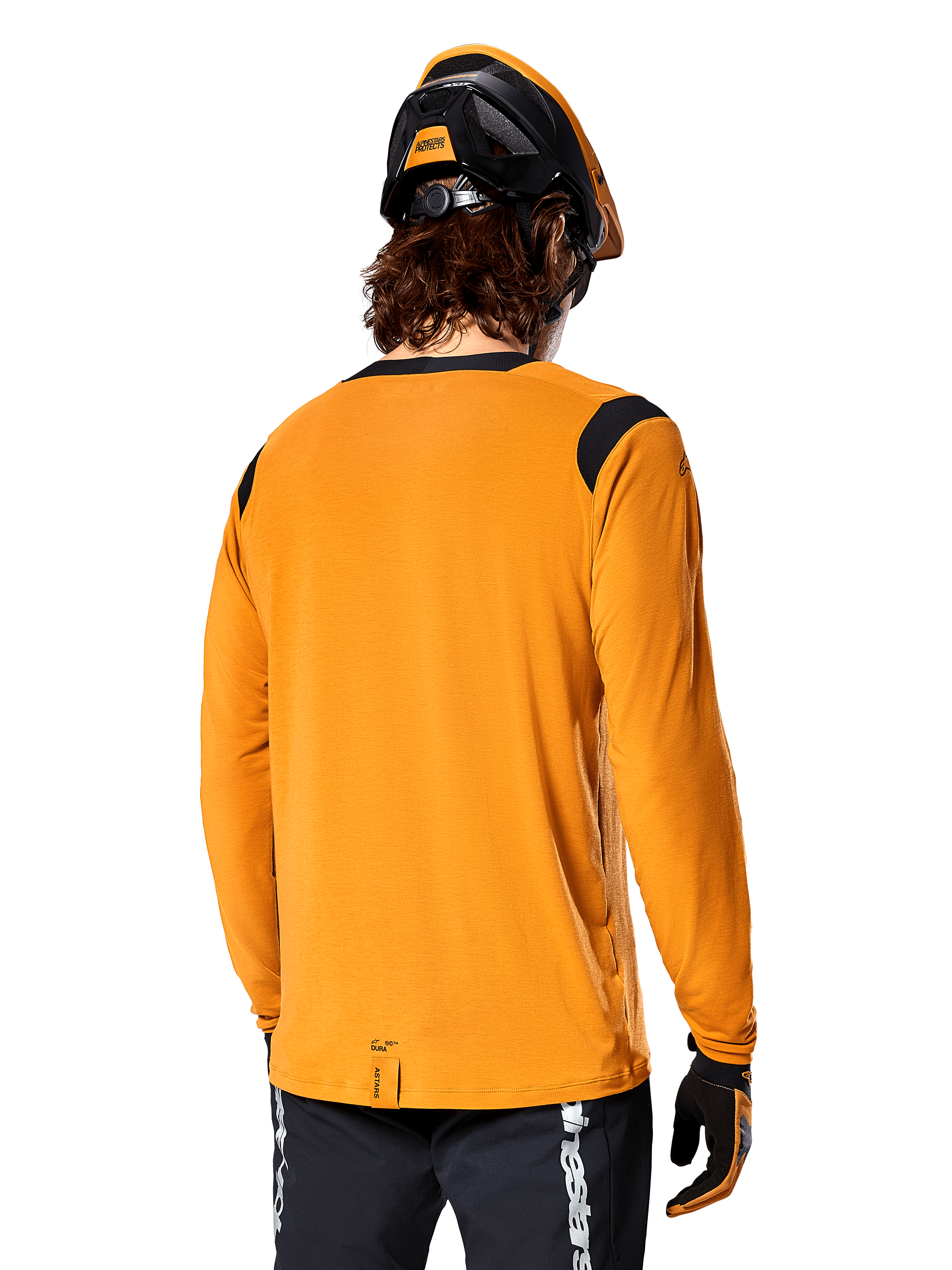 Jersey de manga larga Alpinestars A-Dura Dri Wool en color Dark Gold, vista posterior de un ciclista con casco de mountain bike y guantes, con paneles de malla negros en los hombros y una parte trasera más larga, ropa técnica de ciclismo para trail