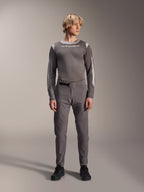 Pantalones Alpinestars A-Dura Elite, pantalones de ciclismo de montaña gris oscuro, vista de cuerpo completo, usados con un jersey de rendimiento de manga larga gris a juego con el logo de Alpinestars, zapatillas negras con detalles rojos, conjunto de ciclismo deportivo