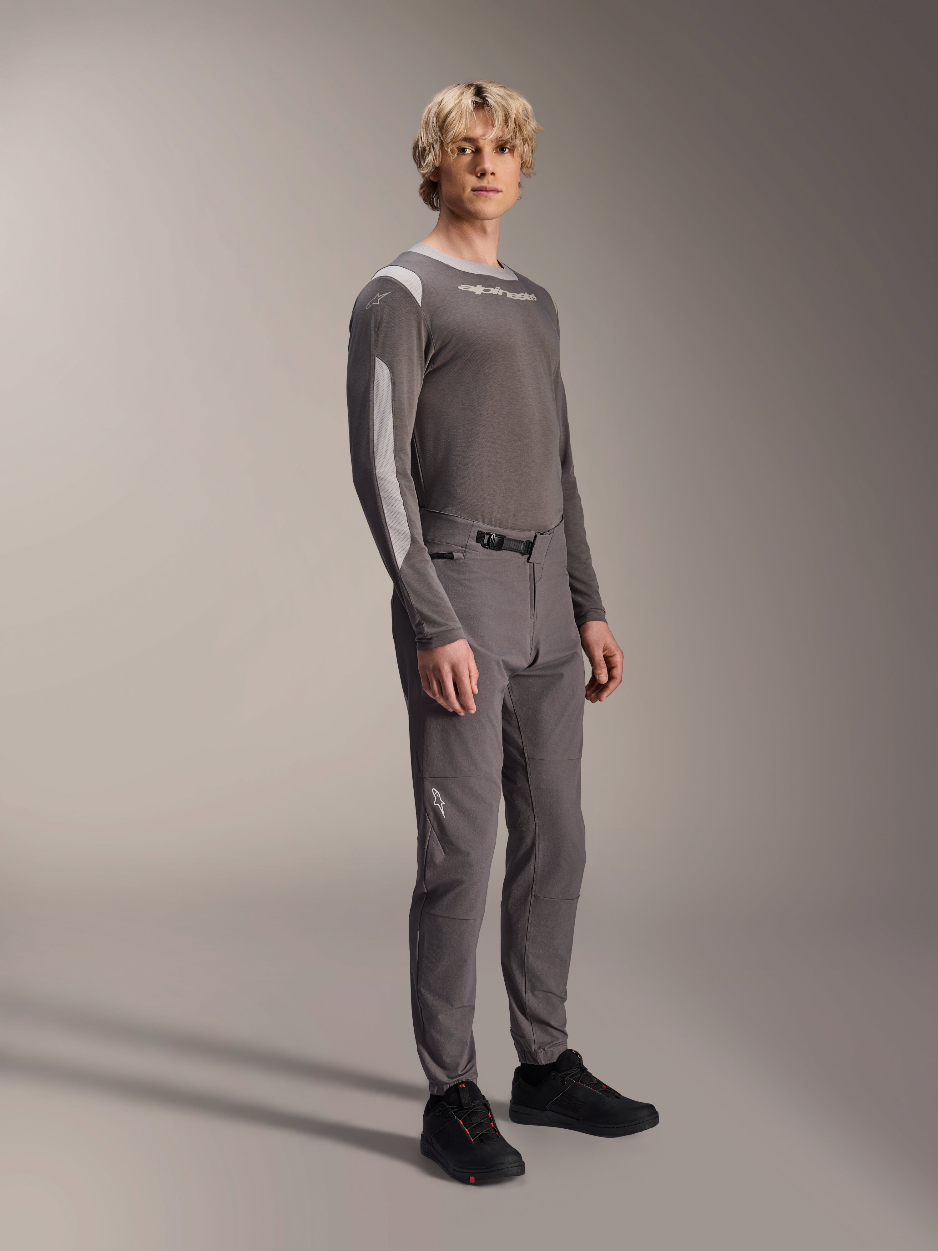 Pantalones Alpinestars A-Dura Elite, pantalones de mountain bike, gris oscuro, usados con un jersey de manga larga a juego y calzado negro, con cierre de trinquete frontal y tejido Cordura resistente para trail y enduro