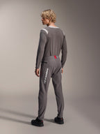 Modelo desde una vista posterior con equipamiento MTB de Alpinestars, jersey de manga larga A-Dura Dri Wool gris, pantalones A-Dura Elite gris oscuro con marca vertical blanca y detalle rojo en la cintura, conjunto de ciclismo coordinado para mountain bike