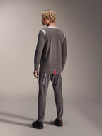 Modelo con jersey Alpinestars A-Dura Dri Wool de manga larga, gris oscuro con paneles de malla en los hombros en gris claro, combinado con pantalones de ciclismo a juego en gris oscuro, vista trasera que muestra el dobladillo trasero más largo, ropa para bicicleta de montaña