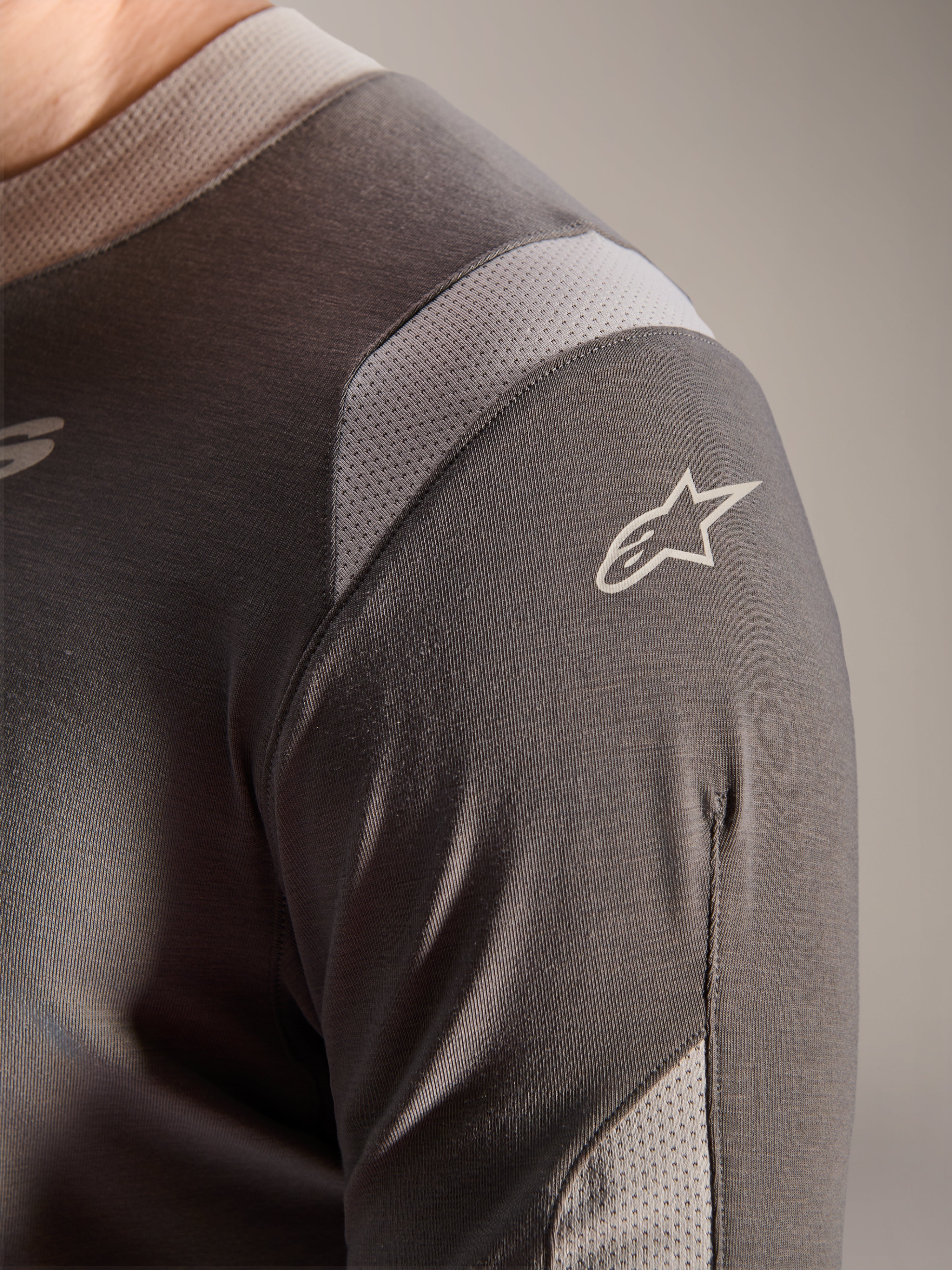 Alpinestars A-Dura Dri Wool Jersey - Manga Larga, gris oscuro, vista detallada del hombro y la manga que muestra paneles de ventilación de malla gris claro y el logotipo blanco de Astars sobre el tejido técnico drirelease.