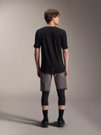 Alpinestars A-Dura Elite Shorts, pantalones cortos de mountain bike en gris oscuro, vista trasera, combinados con un jersey negro de manga corta, rodilleras y calcetines negros, equipamiento técnico de ciclismo para recorridos off-road