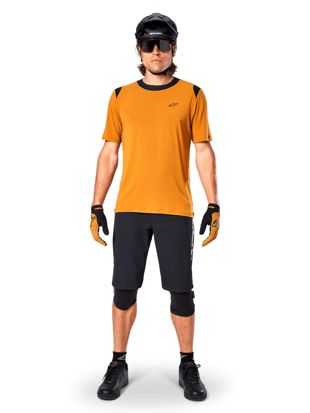Jersey de manga corta Alpinestars A-Dura Dri Wool en color Dark Gold, jersey de mountain bike usado con pantalones cortos negros y equipo de protección, tejido amarillo mostaza con cuello y detalles en los hombros en negro, ropa de ciclismo de alto rendimiento para rodar por senderos.