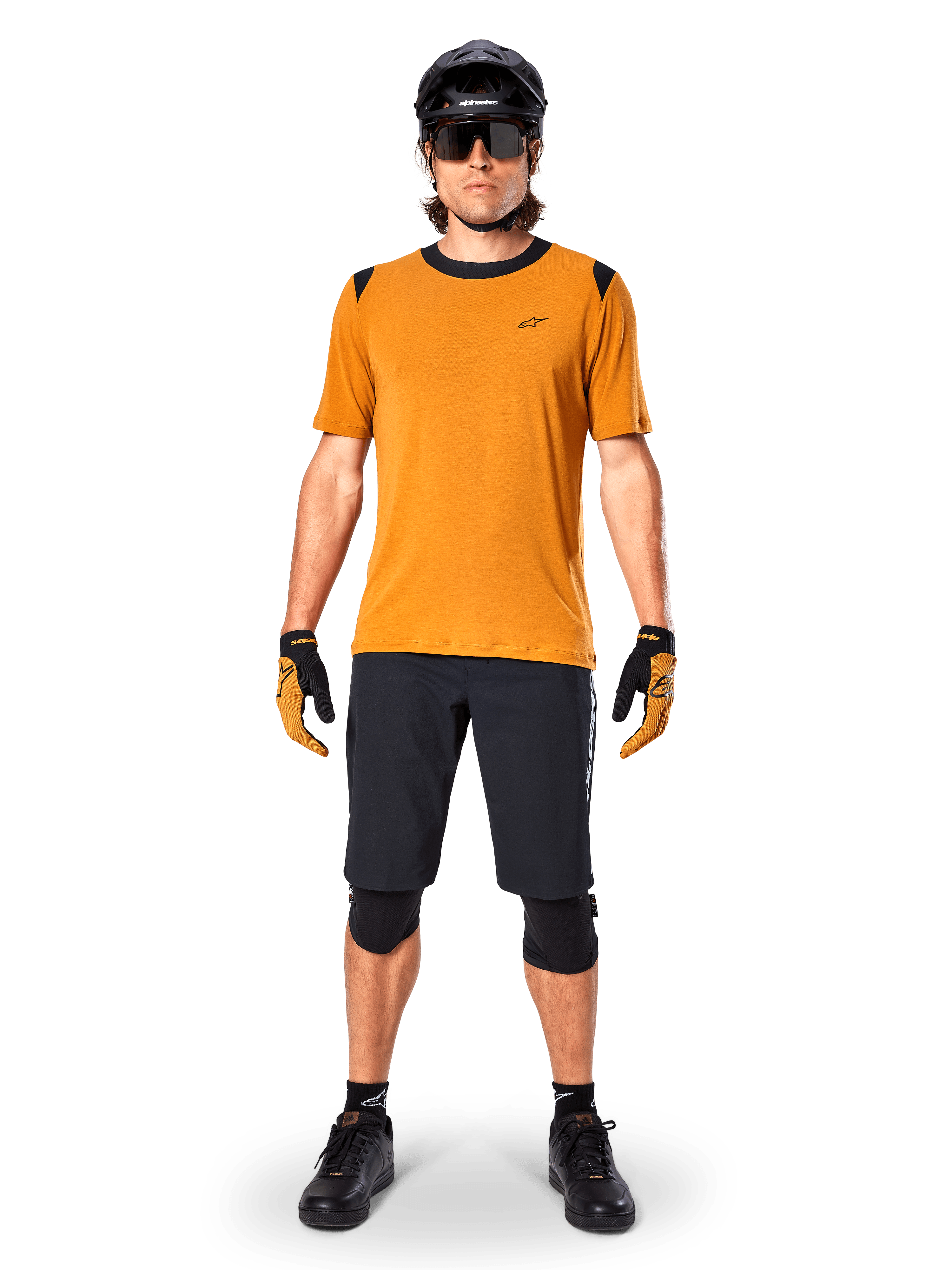 Jersey de manga corta Alpinestars A-Dura Dri Wool en color Dark Gold, jersey de mountain bike usado con pantalones cortos negros y equipo de protección, tejido amarillo mostaza con cuello y detalles en los hombros en negro, ropa de ciclismo de alto rendimiento para rodar por senderos.