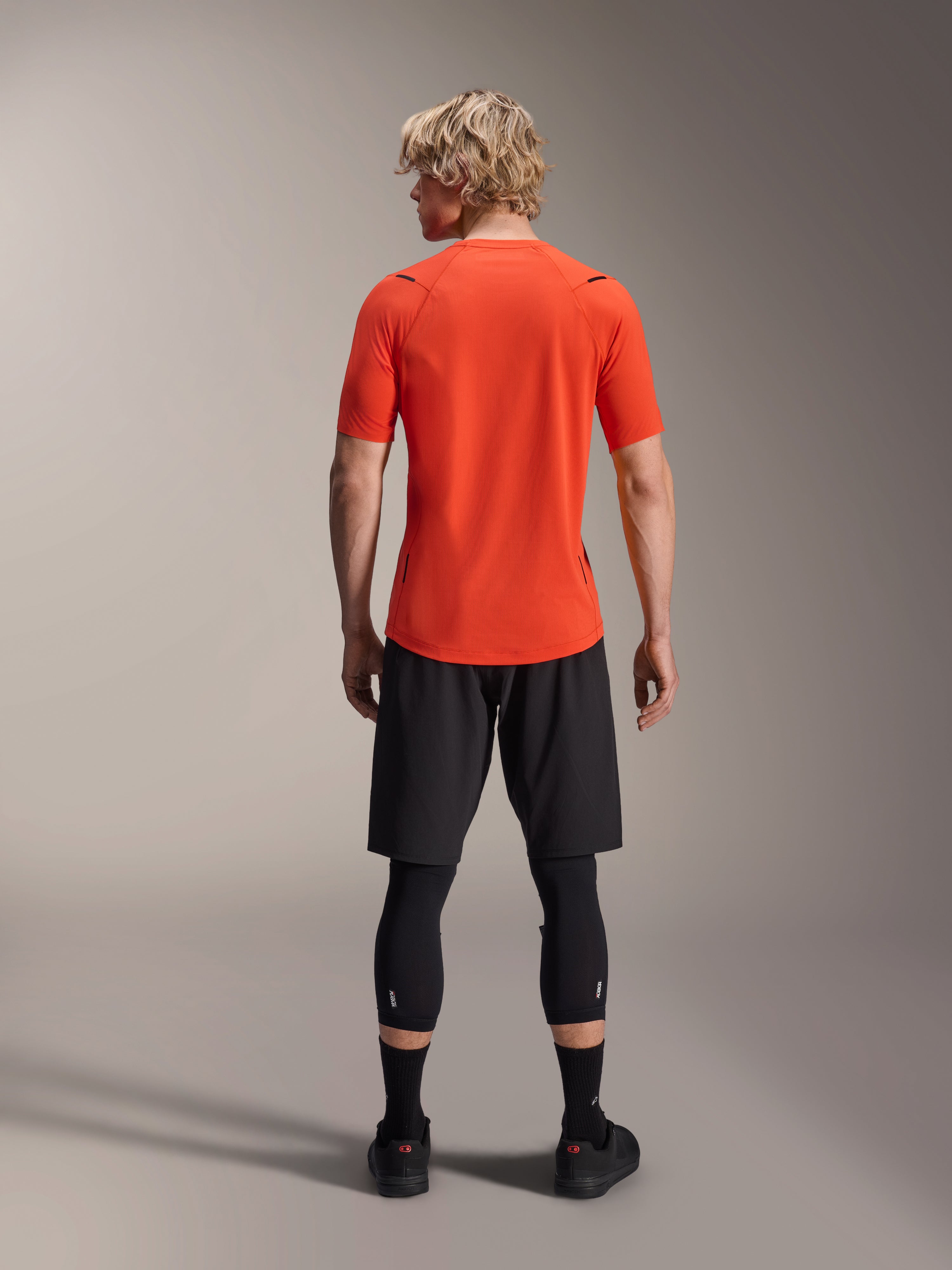 Alpinestars A-Aria Astar Jersey, jersey de MTB de manga corta, Spicy Orange, vista posterior que muestra el ajuste de rendimiento y la cola caída más larga, combinado con pantalones cortos de ciclismo y mallas negras