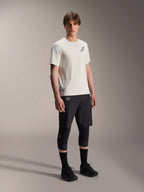 Jersey Alpinestars A-Aria Astar de manga corta, color crudo, con logotipo negro en el pecho, combinado con pantalones cortos de ciclismo y rodilleras negros, equipamiento ligero de alto rendimiento para MTB