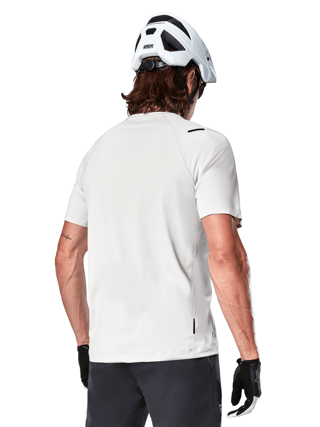 Alpinestars A-Aria Astar Jersey, manga corta, blanco (White Dove), vista trasera de este jersey de ciclismo de montaña ligero y transpirable, usado con casco blanco y guantes de ciclismo negros, con una parte trasera más larga para mayor cobertura